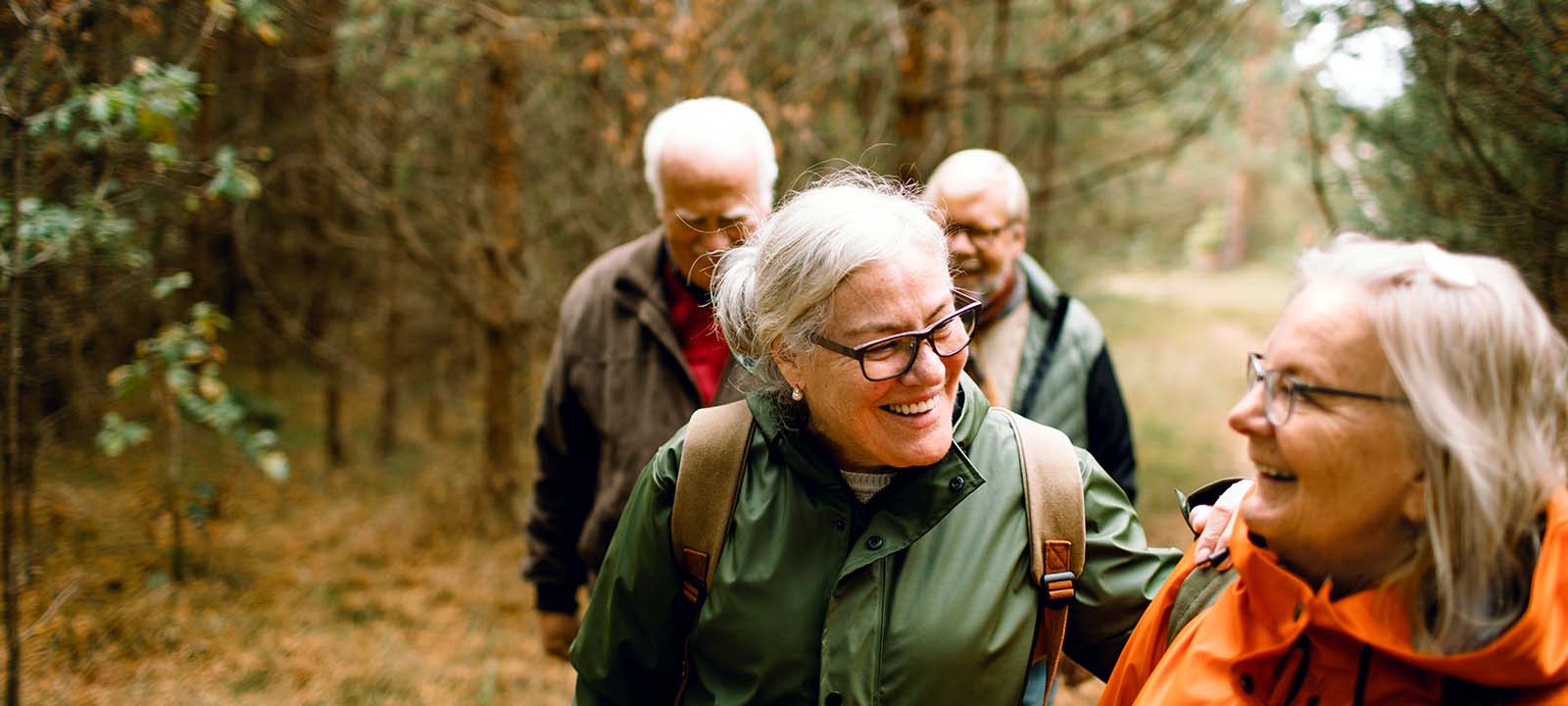 Older adults smiling and walking in the woods | National Lutheran Communities & Services