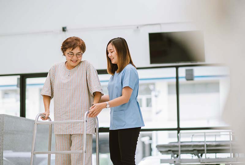 Caregiver helping resident in walker | National Lutheran Communities & Services