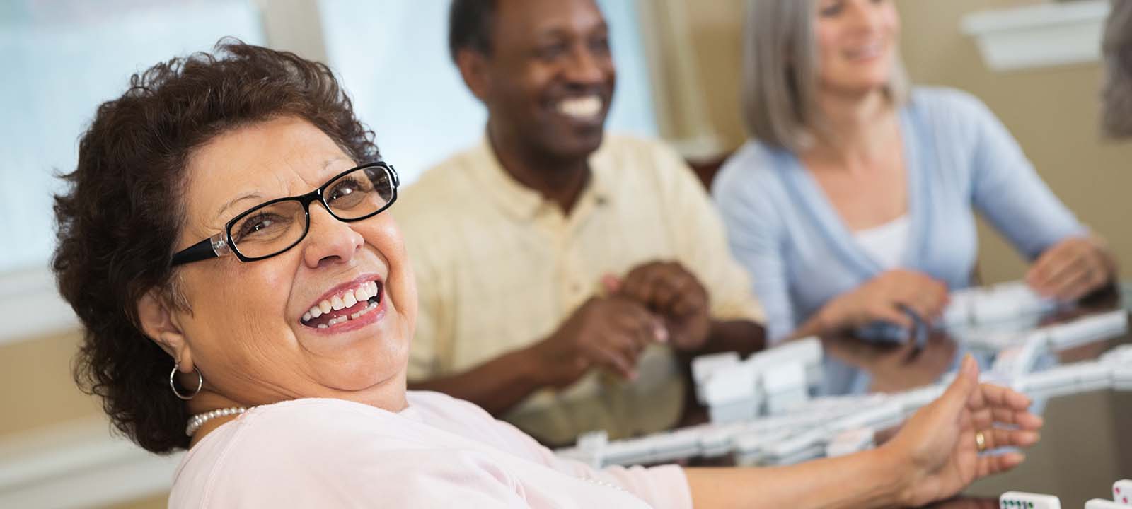 Residents smiling and playing dominos | National Lutheran Communities & Services