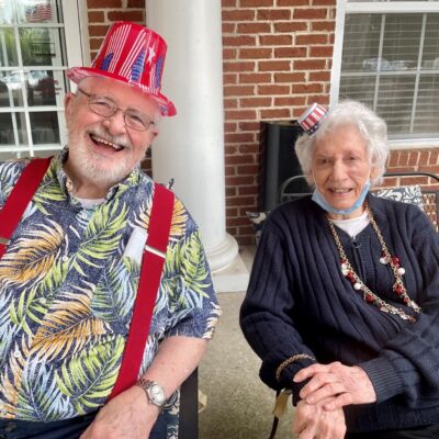 Residents smiling for a photo with American flag hats | National Lutheran Communities & Services